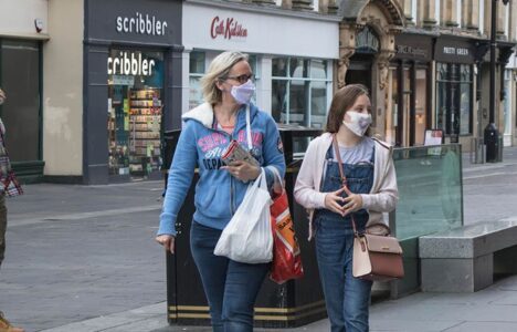 Two women walking on the street with masks on during covid
