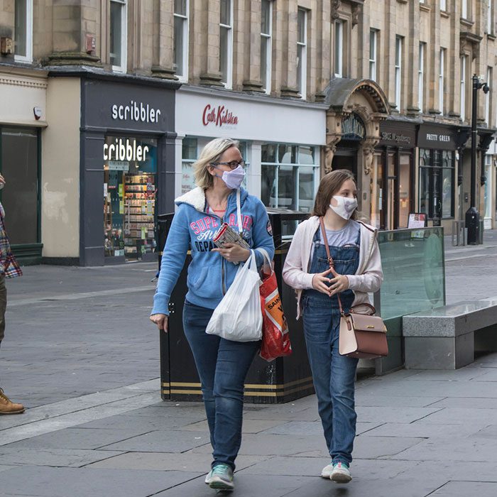 Two women walking on the street with masks on during covid