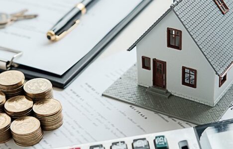 House model next to piles of coin and calculator