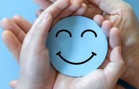 People hold blue smiley face in palms