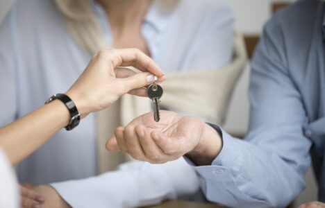 Couple of homeowners getting key to new house apartment from realtor, happy real estate owners make purchase deal, family mortgage investment and buying property concept, close up view of hands