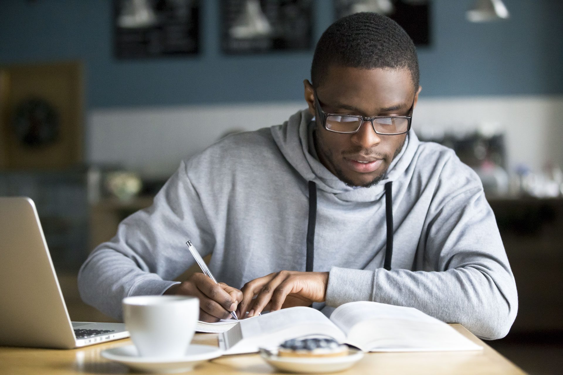 Student studying in a cafe in London with laptop and books on the table