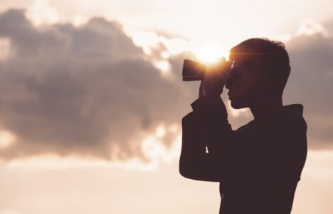 Asian man Hand Holding Binoculars / looking / watching using Binoculars with copyspace,Concept of The pursuit of profitable business in the future.