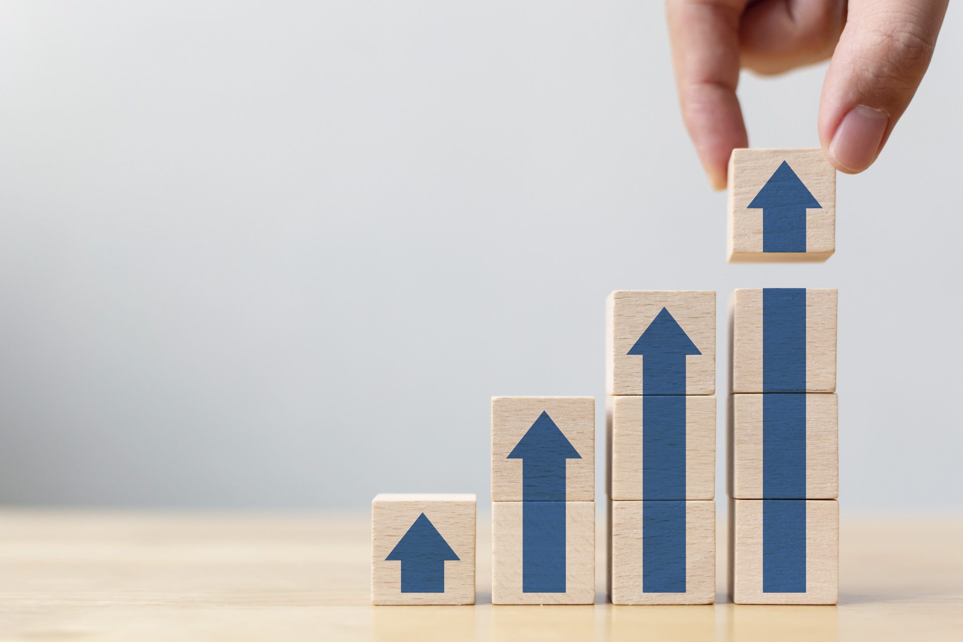 A hand is stacking blocks with arrow facing upward.