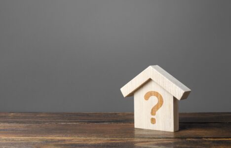 Question mark on a wooden house representing the real estate market and related situations