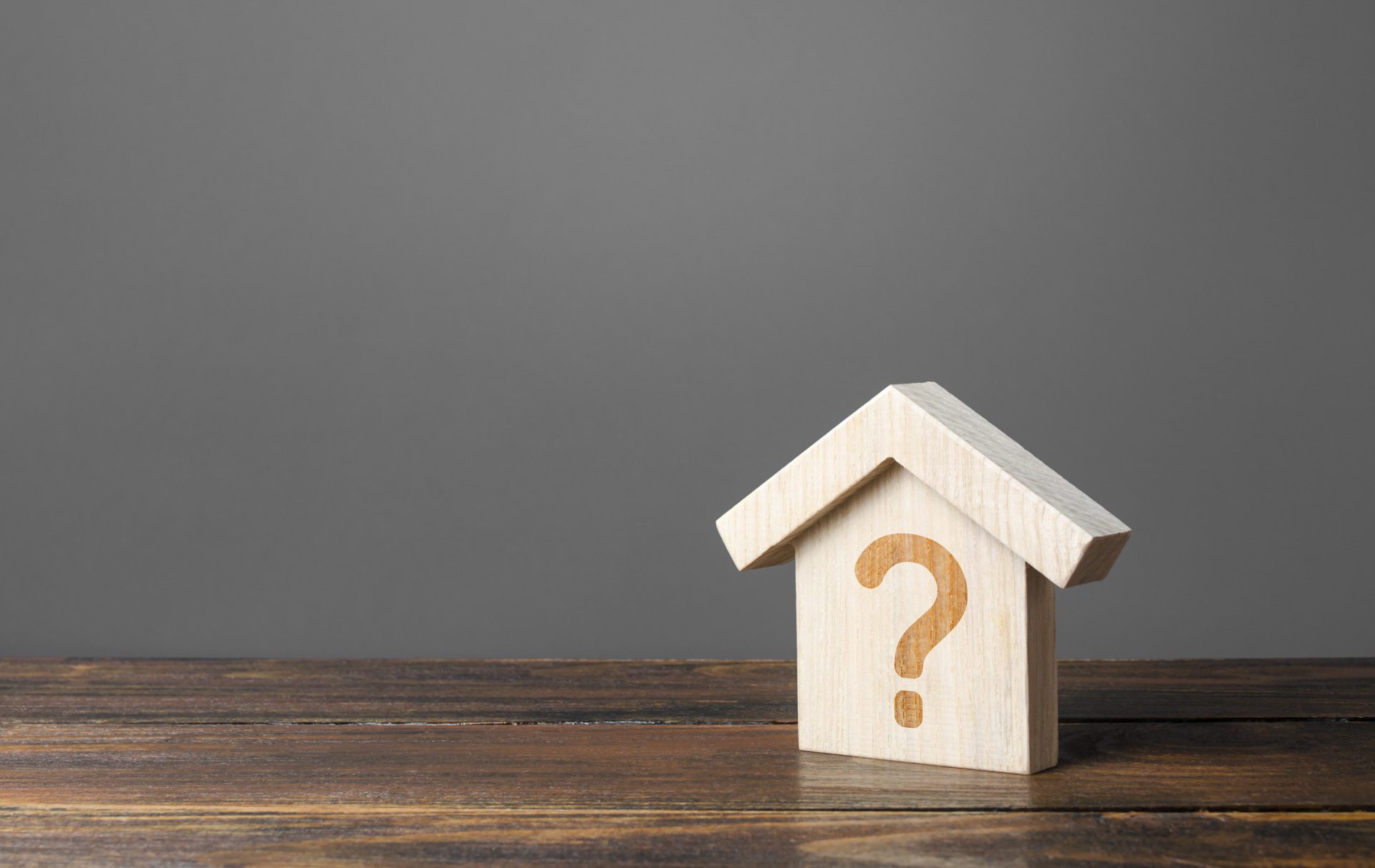 Question mark on a wooden house representing the real estate market and related situations
