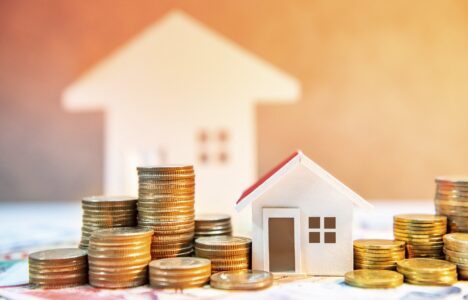 Real estate or property investment. Home mortgage loan rate. Saving money for retirement concept. Coin stack on international banknotes with house model on table. Business growth background