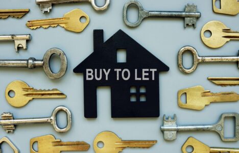 House shape in black with 'buy to let' text surrounded by keys on blue background