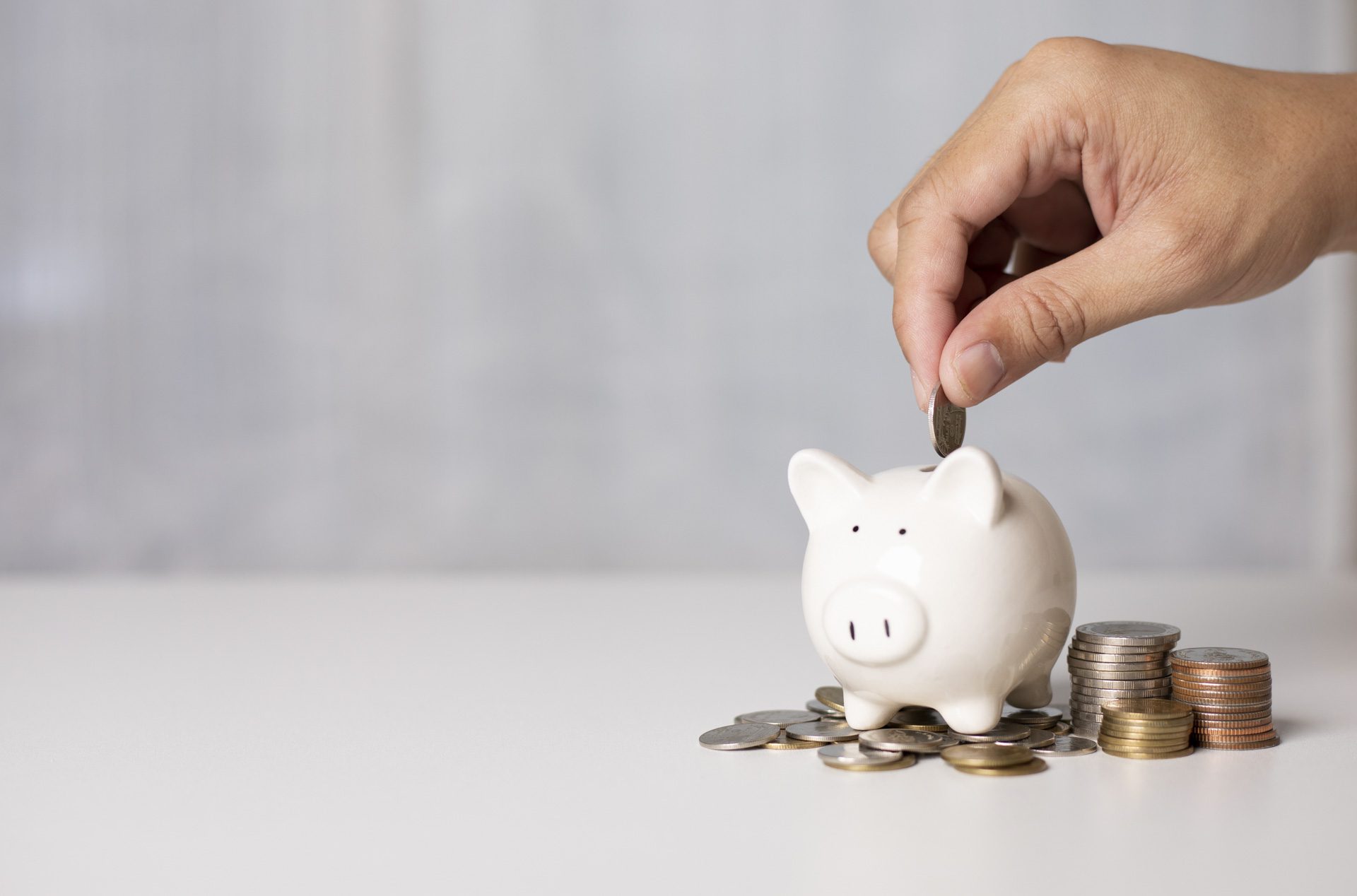 Hand putting a coin in piggy bank. a pile of coins, business, investment, finance, and Money Saving for future concepts, save money.