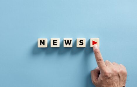 Male hand presses the play button with the news on wooden cubes. Broadcasting, publishing or watching the latest news concept.