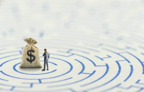 Reducing or overcome financial barrier, financial concept : US dollar bag on a maze puzzle with a businessman considers how to overcome financial difficulties. CFO wishes to avoid a financial crisis.