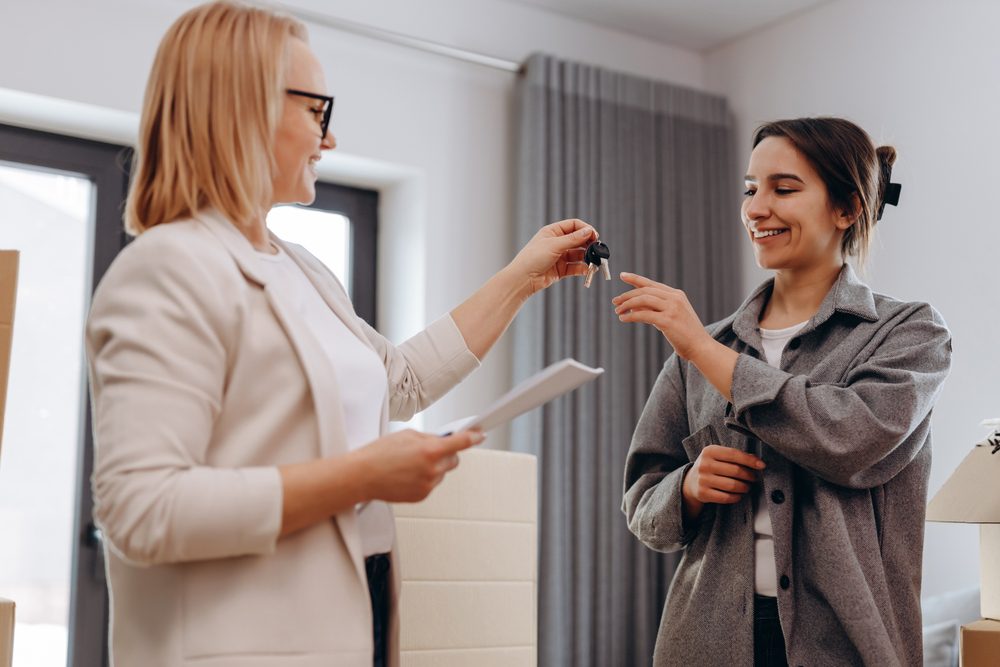 two female exchanging keys and documents