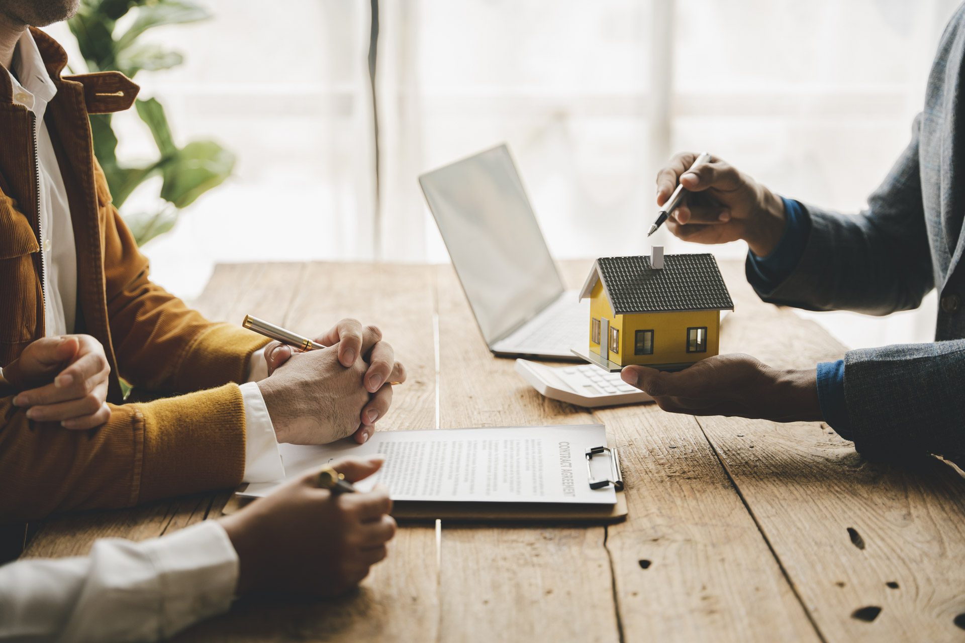 Home buyers ready to sign a contract and seller holding a model house