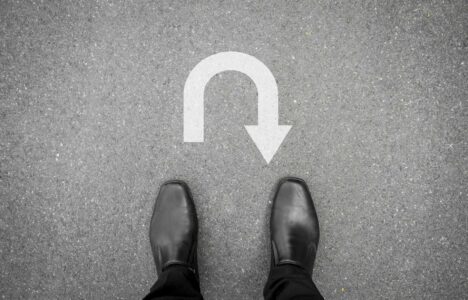 black shoes standing on the asphalt concrete floor in front of u turn symbol