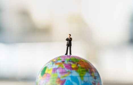Property investor model standing on top of a globe to represent overseas real estate investment