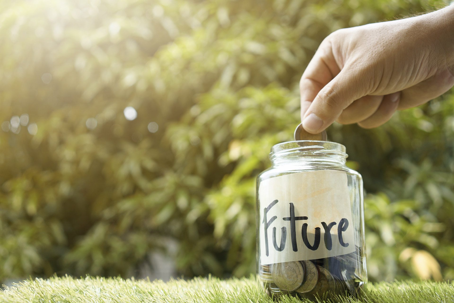 Hand puts coins into a jar with text 'Future'.