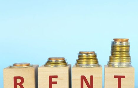 Piles of coin on top of blocks that write 'R E N T'.