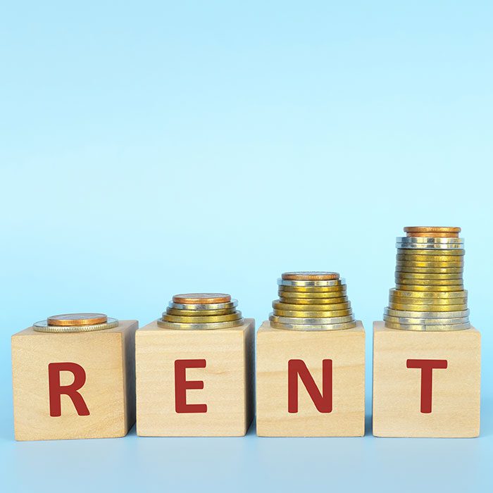 Piles of coin on top of blocks that write 'R E N T'.