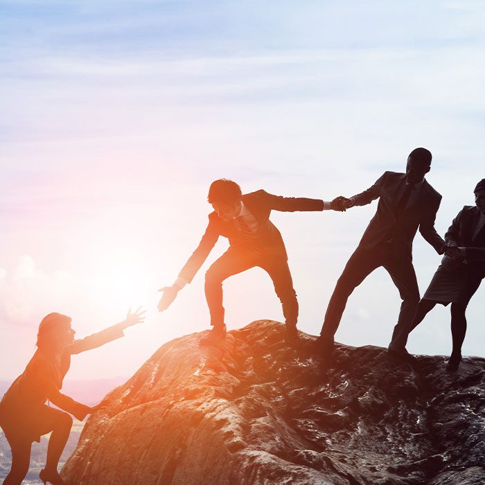 People helping each other to get to the top of a mountain
