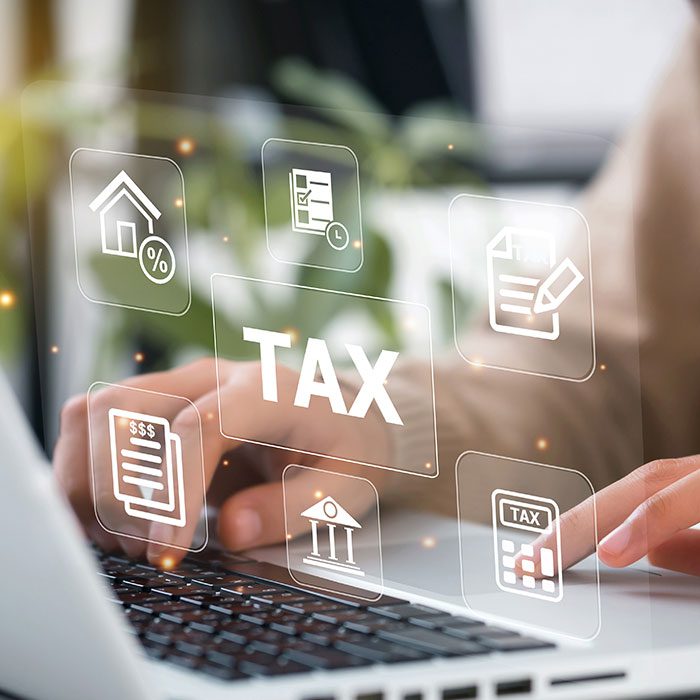 Person typing on a laptop with tax hologram