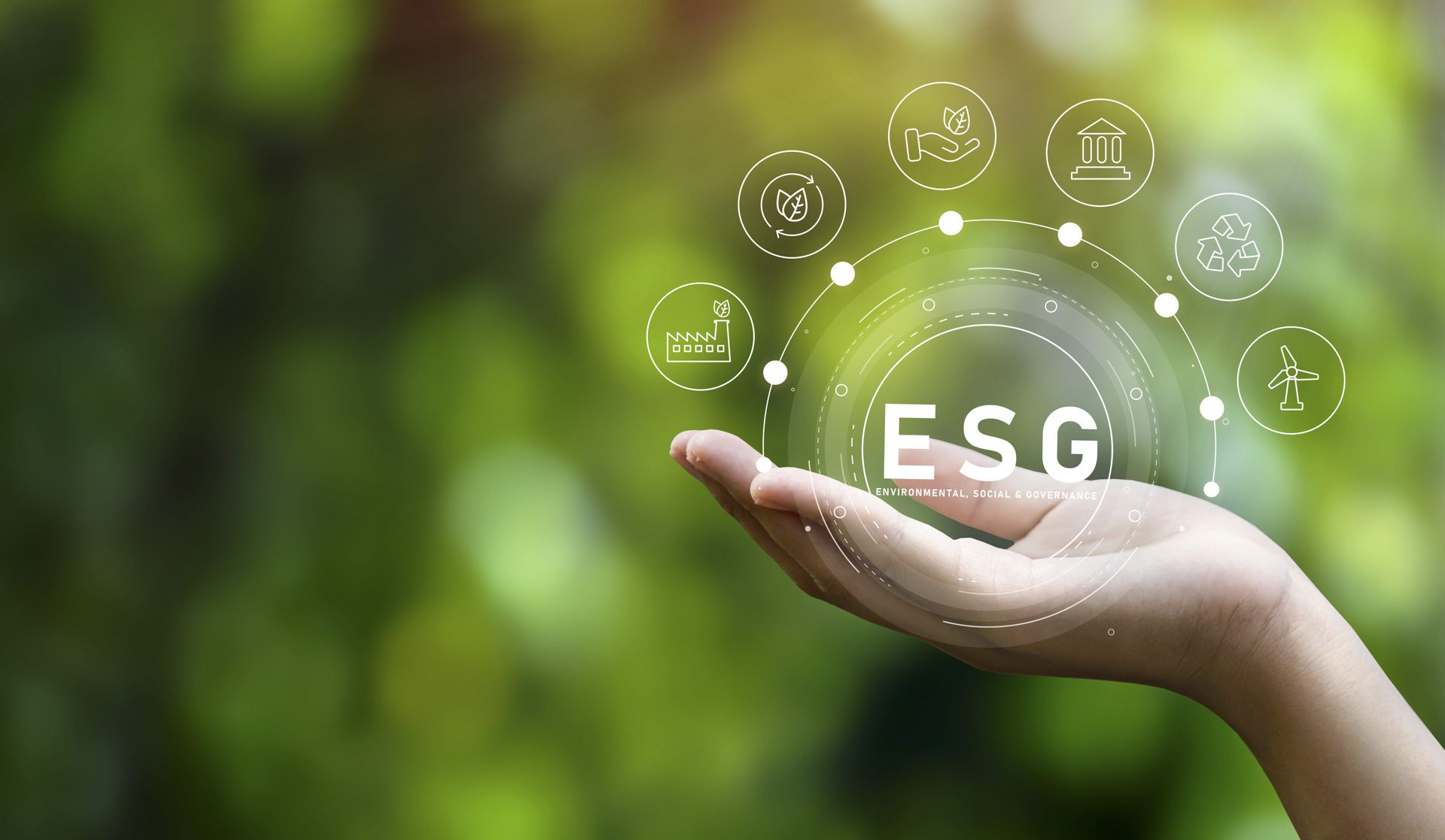 Hand holding ESG icon, signifying environmental, social and governance in sustainable business, on green background