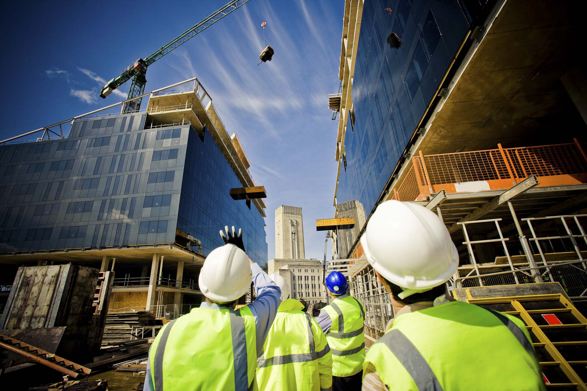 Off plan property construction site with workmen looking upwards at the development being built