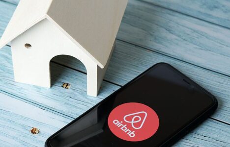 Airbnb app on a mobile phone right next to a house model