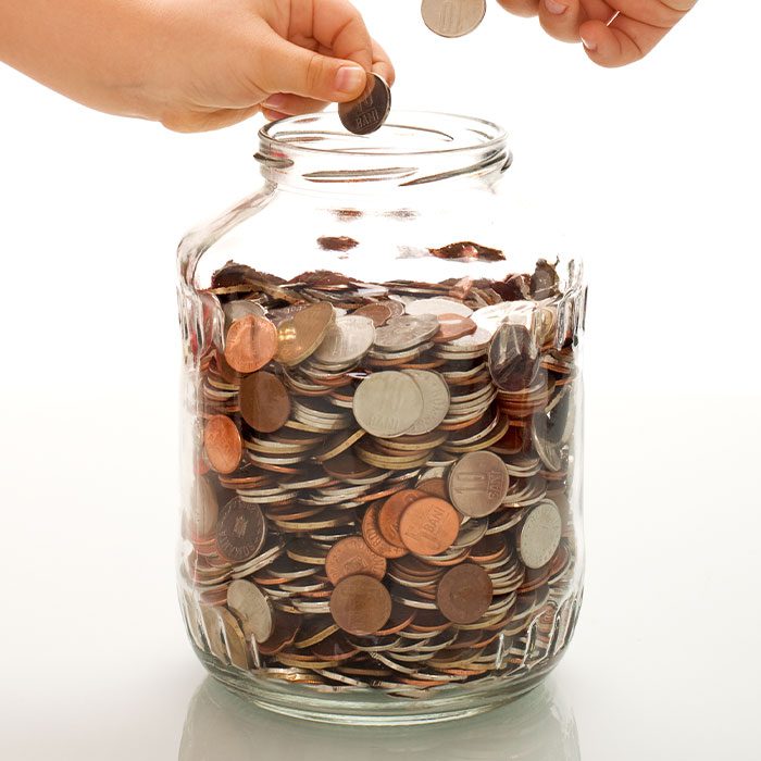 Hands putting coins in a jar
