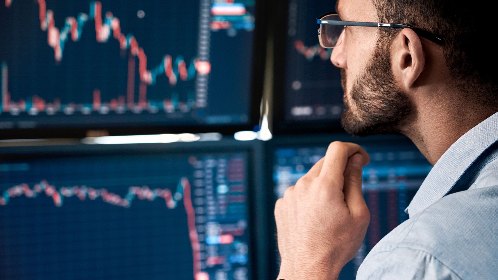 Expert stares at four screens with market data