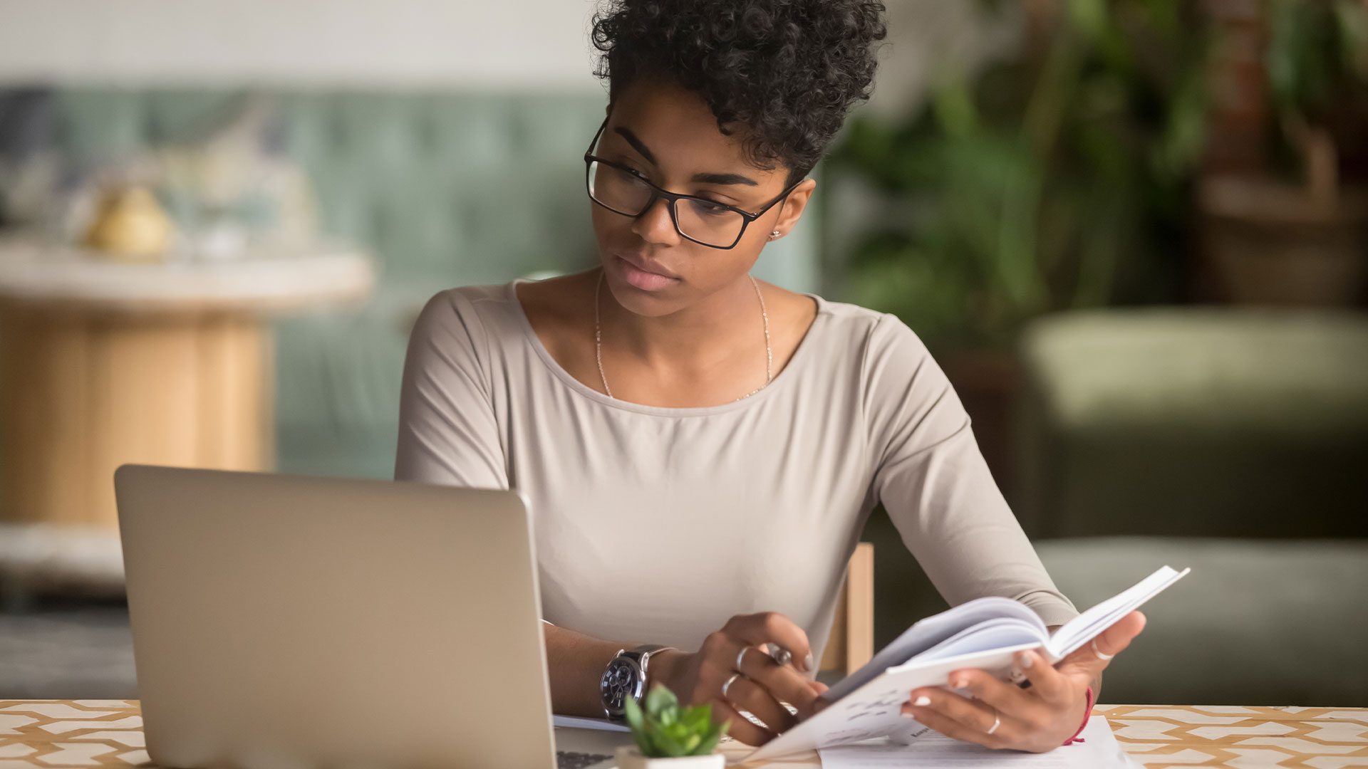 Lady flips book and looking at her laptop