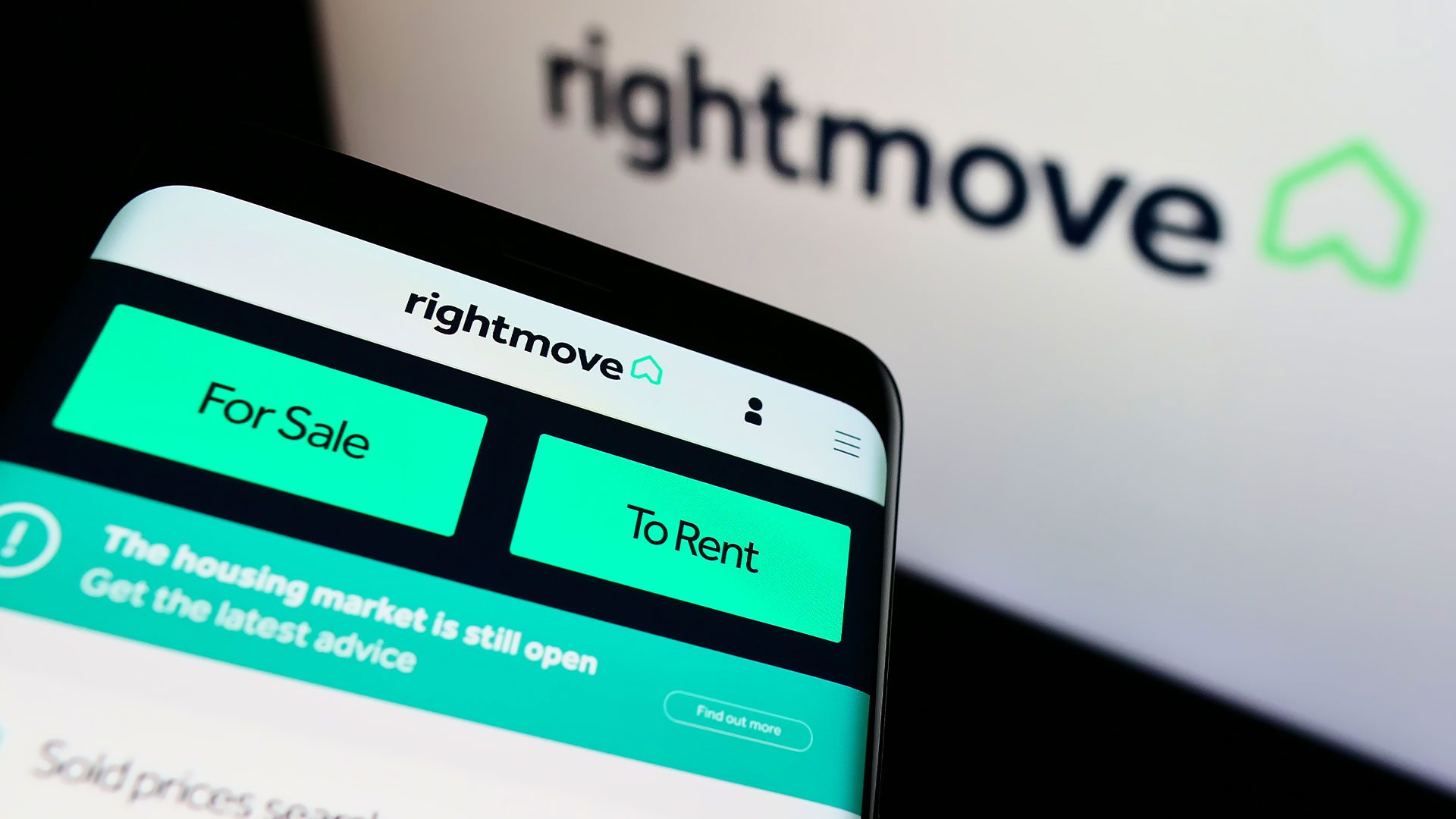 A phone with the Rightmove app and a computer showing the property portal's website for real estate market research
