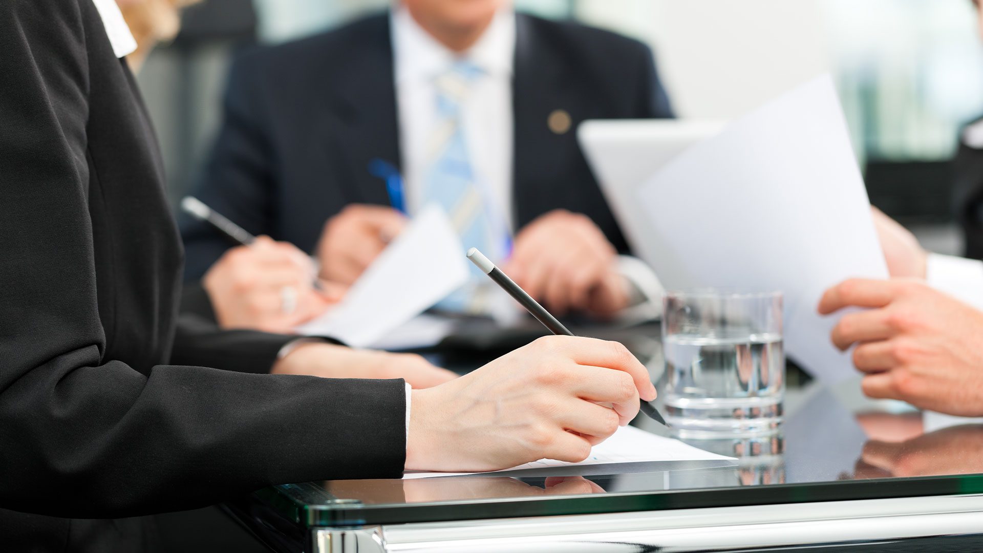 Business people sit down and discuss about property investment at a table in an office with pens and paper