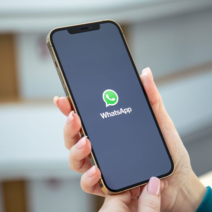 A hand holding a mobile phone with WhatsApp open signifying contacting RWinvest