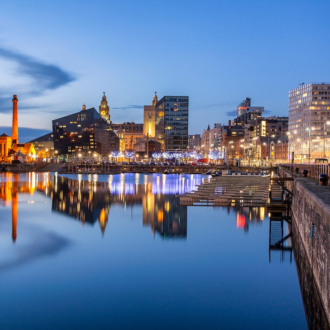 Liverpool waterfront at dusk, with the Three Graces illuminated.