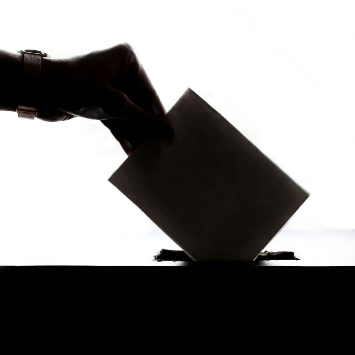 hand putting a voting slip into a ballot box