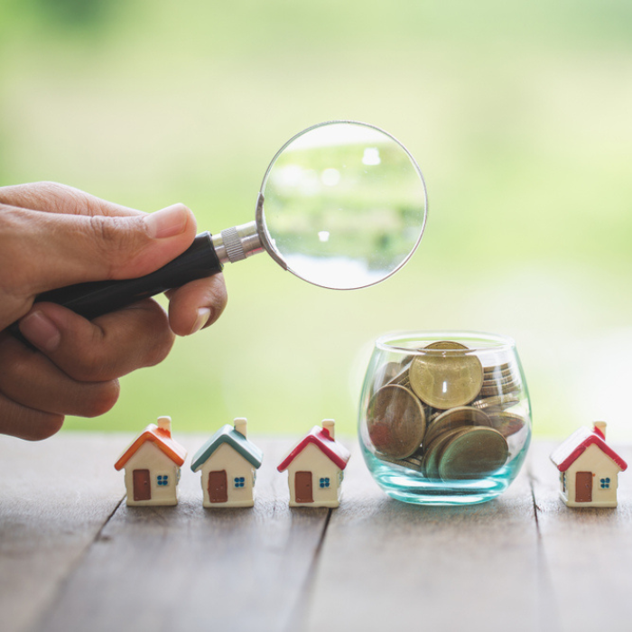 Investor searching for houses. A small glass bottle to put coins together.