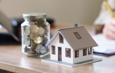 Stock image depicting property investment with model of house and money beside it