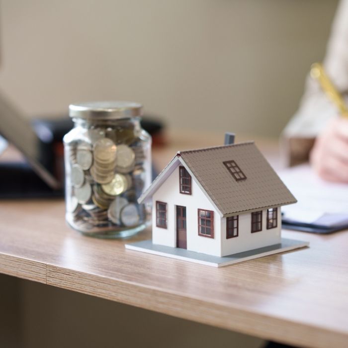 Stock image depicting property investment with model of house and money beside it