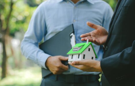 Businessmen holding a model of an eco-friendly house with green roof