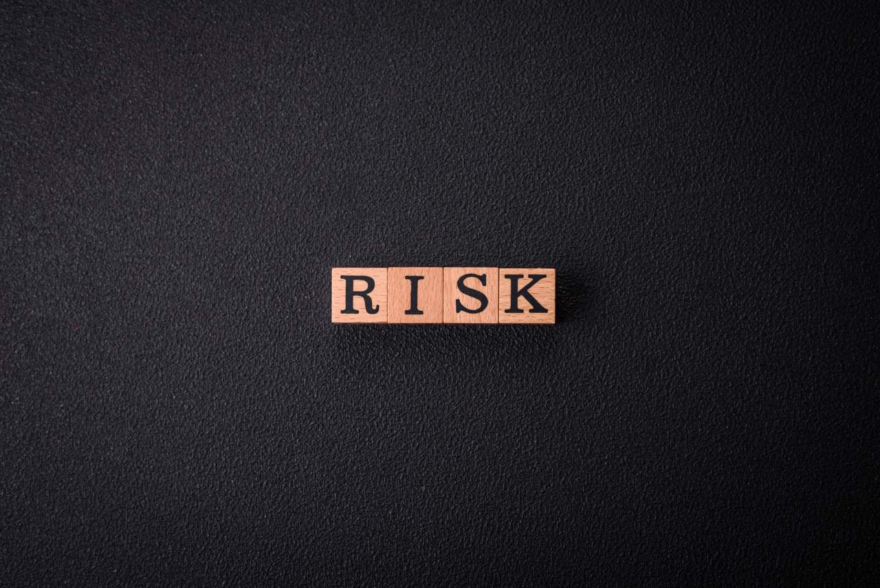 word risk spelled on wooden cubes on black background