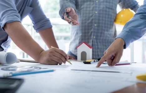 men discussing on desk with blueprint about new property project
