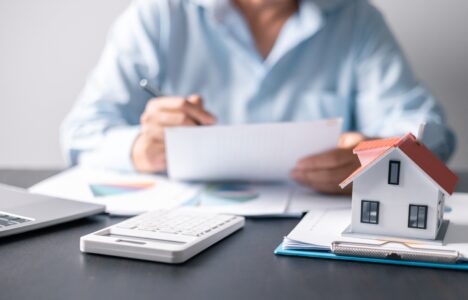 Stock image showing man at desk with paperwork and model of a house