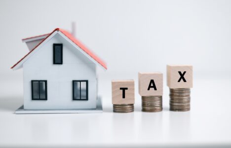 miniature house with word tax on wooden blocks