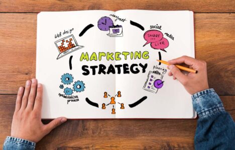 person holding a pen and a paper with colorful sketches with the words marketing strategy written in the middle