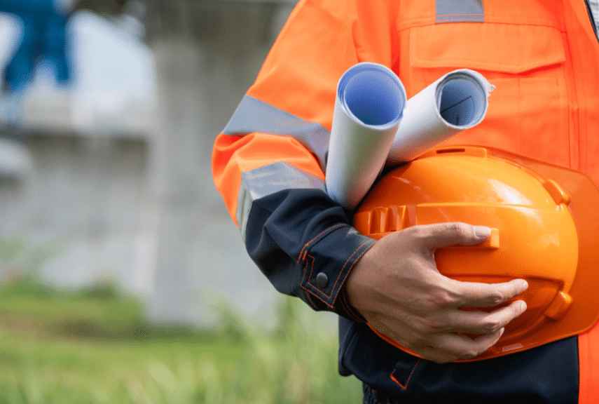 Construction worker in orange high-vis holding orange hardhat